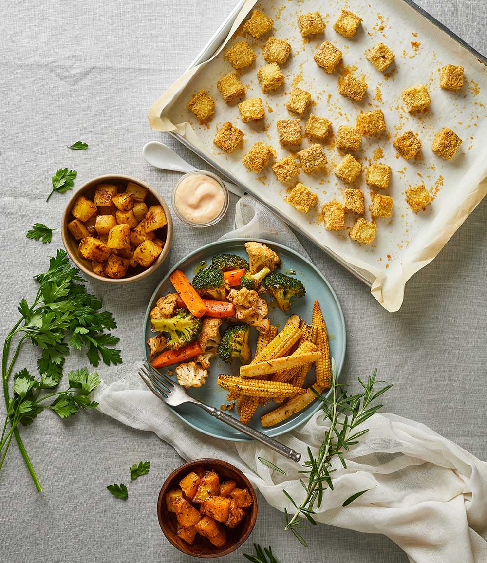 Roasted potatoes, vegetables and baby corn with a tray of baked tofu