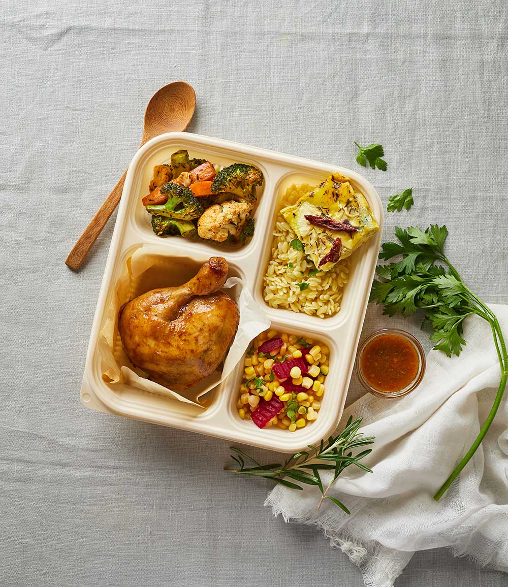 A bento box with chicken, pasta, vegetables and corn